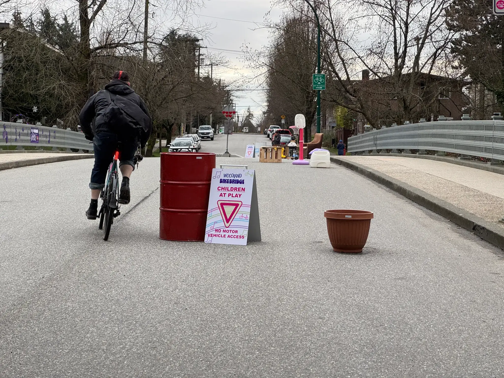 A cyclist passes the barriers and signage on the Woodland BikeBridge